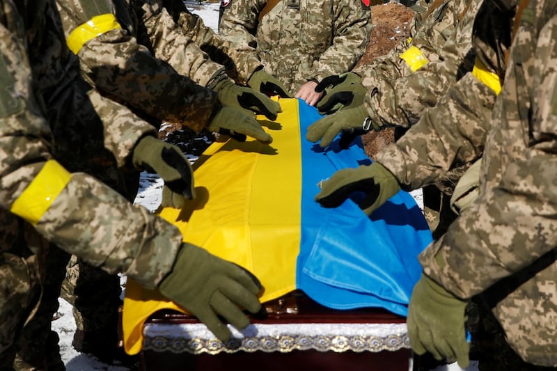 Members of the Honour Guard place the national flag to a coffin with a body of the member of the Ukrainian Armed Forces, Valerii, who was killed during Russia's invasion of Ukraine, during a funeral ceremony in Kyiv, Ukraine, March 8 2022.